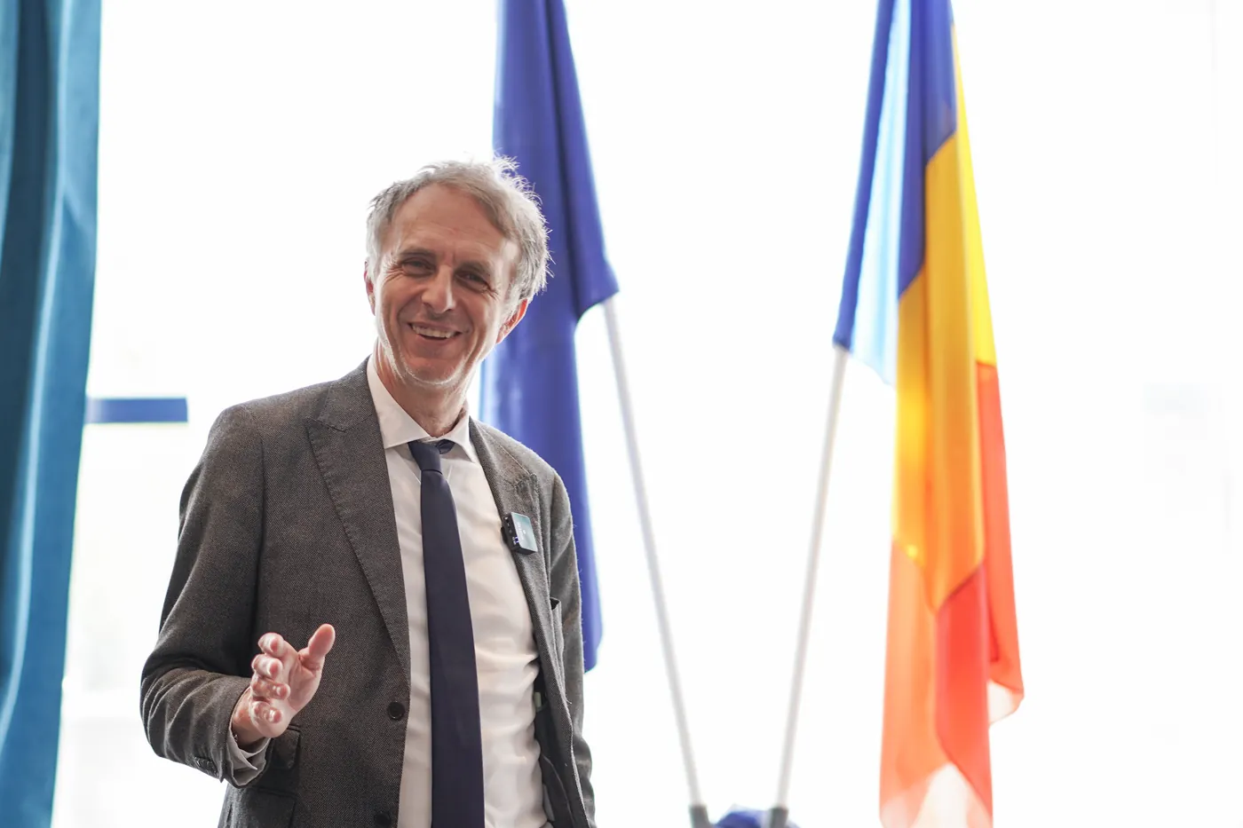 Dr. Marco Paret speaking in front of the European Union and Romanian flags at a psychiatry conference in Oradea